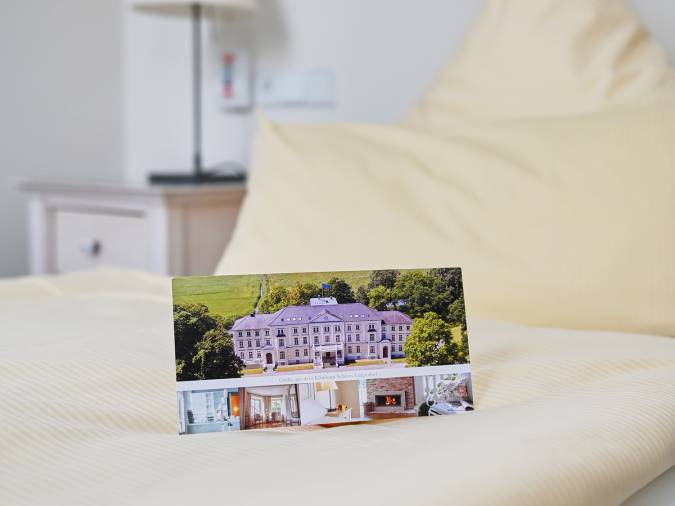 Ein gemütliches Schlafzimmer mit einem einladenden Bett und einem Infoheft, das auf der Bettdecke liegt.