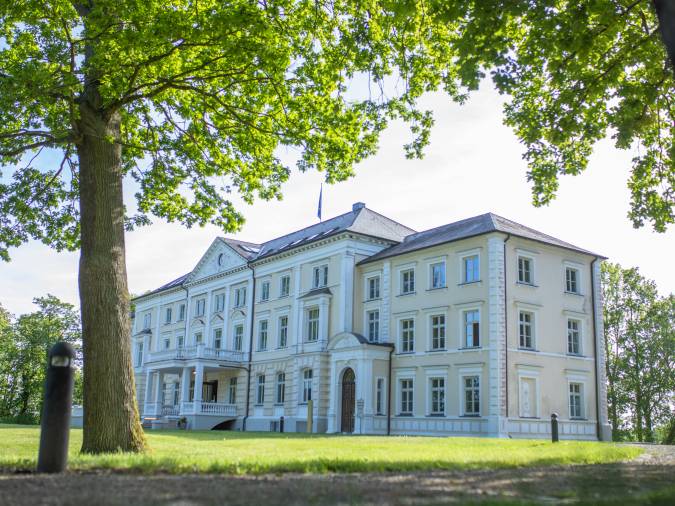 Außenansicht des Klinikums, ein imposantes, weißes Gebäude in einer idyllischen Umgebung.