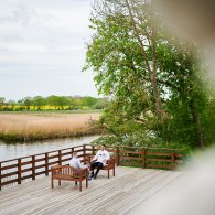 Zwei Personen, ein Arzt und ein Patient, sitzen auf einer Terasse und führen ein einfühlsames Gespräch.