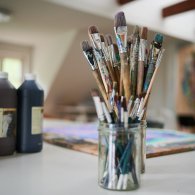 Ein Glas mit Pinsel, bereit für kreative Kunsttherapie und Ausdruck von Emotionen durch Malerei.