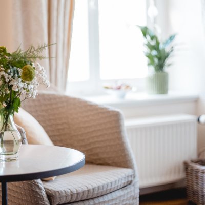 Ein Stuhl in einem Klinikzimmer, auf dem ein Vase mit bunten Blumen steht, die eine beruhigende Atmosphäre schaffen.